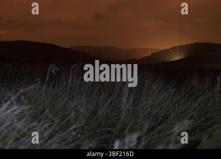 Eine schottische Landschaft bei Nacht mit Lichtern am Himmel in der Ferne und Lichtmalerei im Winter in Tomintoul in den Highlands von Schottland Stockfoto