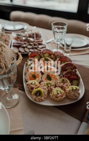Eine Nahaufnahme eines wunderschön gestalteten Tisches mit einem langen Teller voller Wurst, Käse, Gemüsespieße und gefülltem Gebäck, Comple Stockfoto
