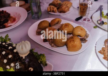 Aus nächster Nähe sehen Sie einen reich gedeckten Tisch voller polnischer kulinarischer Köstlichkeiten, darunter Fleischscheiben, Knödel, Brötchen, eine dunkle Schokoladenkuche und Glas Stockfoto