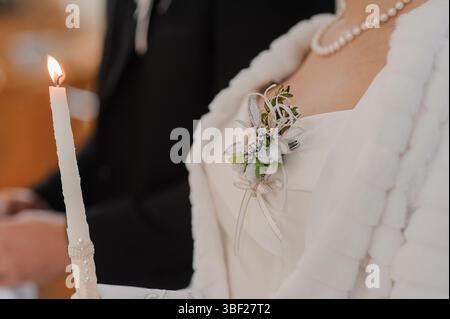 Intimer Blick auf eine Hochzeitskerzenzeremonie mit einer Braut, die eine weiße Pelzstola trägt und einen Bräutigam mit Perlenkette in formeller Kleidung trägt, die Einheit und fai symbolisiert Stockfoto