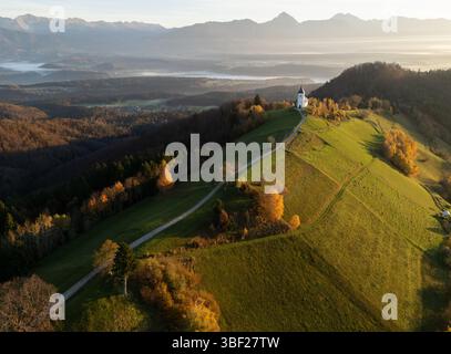 Bergwelt mit einer kleinen Kirche auf einem Hügel und Bergen im Hintergrund, Slowenien Stockfoto