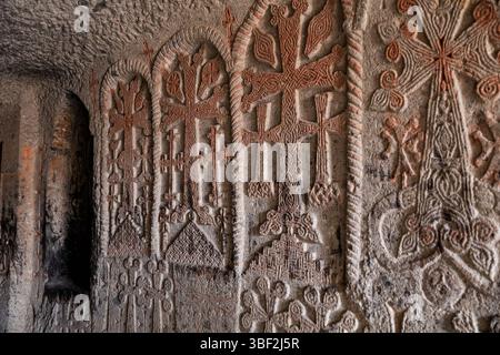Geghard, Armenien - 23. März 2024: Innenraum eines antiken armenischen Tempels im Geghard-Kloster. Tunnel mit geschnitzten Kreuzen an den Wänden (Khachkar) Stockfoto