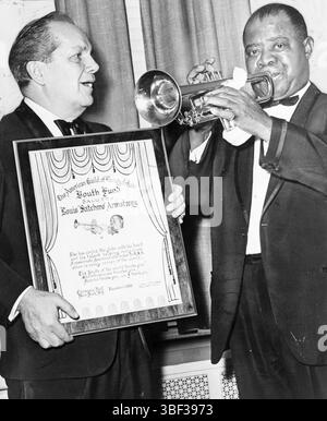 Louis Armstrong spielt Trompete, während Joey Adams, Präsident des American Guild of Variety Artists Youth Fund, ihm einen Preis in der Carnegie Hall verleiht. Louis Daniel Armstrong (4. August 1901 – 6. Juli 1971), auch Satchmo genannt, war ein US-amerikanischer Trompeter und Sänger. Er gehörte zu den einflussreichsten Persönlichkeiten des Jazz. Am Ende seines Lebens hatte sich sein Einfluss auf die Volksmusik ausgebreitet. Er war einer der ersten populären afroamerikanischen Entertainer, der sich bei weißem und internationalem Publikum zu großer Beliebtheit entwickelte. Armstrong sprach selten öffentlich über Rassenfragen, manchmal zum Unmut Stockfoto