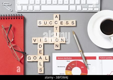 Business Motivation Konzept mit Wörtern aus Cubes. Stillleben des Büroarbeitsplatzes mit Kreuzworträtsel. Flache graue Oberfläche mit pc-Tastatur und Becher Co Stockfoto