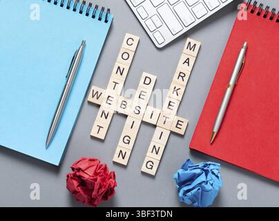 Web-Marketing-Konzept mit Wörtern aus Cubes. Stillleben des Büroarbeitsplatzes mit Kreuzworträtsel. Flache graue Oberfläche mit pc-Tastatur und Notebook. Neue s Stockfoto