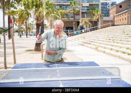 Reifer Mann, der im Tischtennisspiel dient Stockfoto