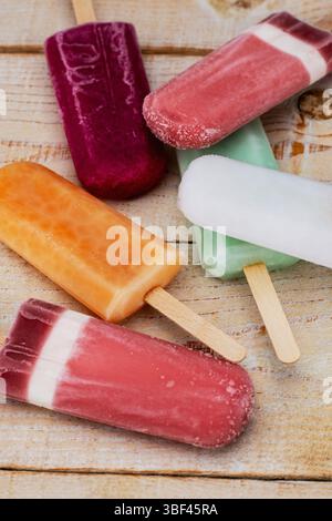 Verschiedene mehrfarbige Eiszapfen auf weißem Tannenholz Hintergrund Stockfoto