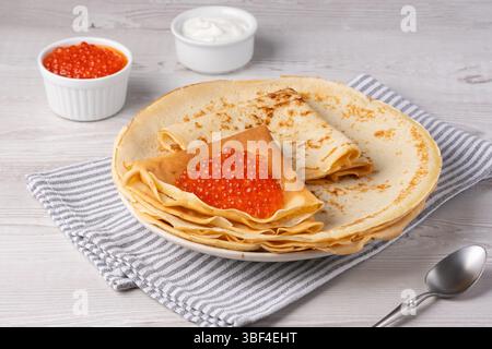 Köstliche Crepes mit rotem Kaviar serviert auf einem gemütlichen Tisch bei Tageslicht Stockfoto