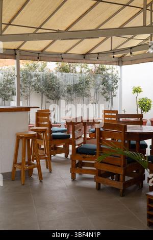 Charmanter Essbereich im Freien mit robusten Holzstühlen, ideal für entspannende Mahlzeiten in einer natürlichen und einladenden Atmosphäre mit zeitlosem Stil. Stockfoto