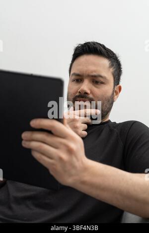 Startup-Gründer prüft Startpläne auf seinem Tablet, während er ruhig in einem sauberen, modernen Büro sitzt. Stockfoto