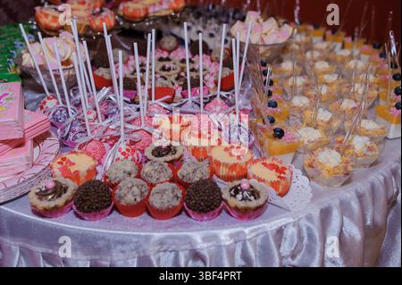 Ein üppiger rosafarbener Nachtisch überfließt mit einer dekadenten Auswahl an Schokolade, Cupcakes, Cake Pops und Obstparfaits, perfekt für eine fröhliche Party Stockfoto
