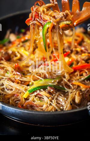 Asiatische Glasnudeln mit Hühnchen und Gemüse in einer Pfanne anbraten Stockfoto