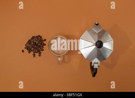 Kaffeekanne, Espresso mit Milch und Kaffeebohnen auf braunem Hintergrund. Stockfoto