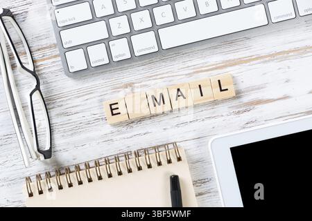 E-Mail-Marketing-Konzept mit Buchstaben auf Würfeln. Stillleben am Arbeitsplatz mit Zubehör. Flacher Vintage-Holzschreibtisch mit Computertastatur und Spirale n Stockfoto
