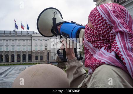 Ein Demonstrant, der einen keffiyeh-Gesang-Slogan durch ein Megaphon trug, während einer Demonstration vor dem Präsidentenpalast. Am Freitag, dem 30. Mai, versammeln sich eine Gruppe palästinensischer Aktivisten und Demonstranten im polnischen Präsidentenpalast in Warschau. Die Demonstranten tragen Banner, Plakate und Fahnen und versuchen, die Präsidentschaftskandidaten an die Präsidentschaftswahlen am Sonntag und ihre Wähler daran zu erinnern, dass der Völkermord in Gaza ein lebendiges und dringliches Thema ist. UN-Generalsekretär Antonio Guterres hat erklärt, dass "die Lage der Palästinenser im Gazastreifen unbeschrieben ist, Mo Stockfoto