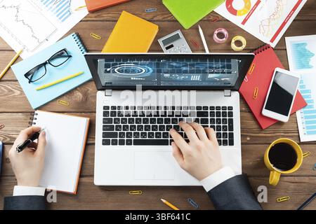 Schließen Sie die Hände eines Geschäftsmannes, die am Laptop arbeiten. Büroarbeitsplatz mit Blick von oben mit Computer und Finanzunterlagen auf Holztisch. Beruf des Unternehmens Stockfoto