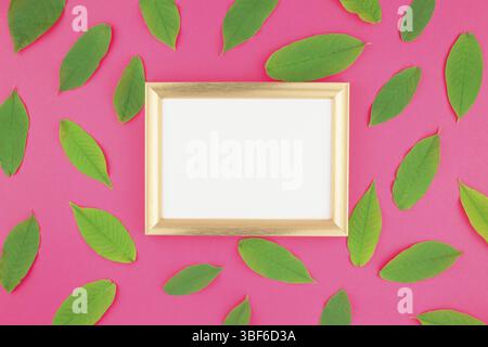 Kreative flach Top view Pattern mit frischen grünen Blättern auf hellem rosa Hintergrund mit goldenen Rahmen mock up und Platz im Minimal Pop Art Stil kopieren Stockfoto