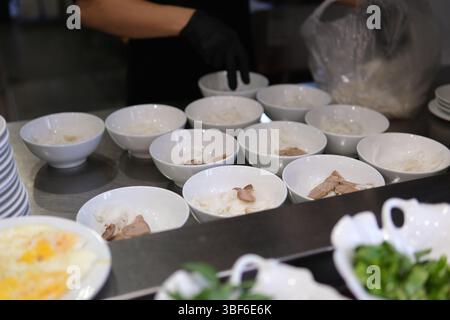 Vietnamesische Pho Suppe Verkäufer Zubereitung Reis Vermicelli Suppe auf der Straße kleines Restaurant Kochen fa Suppe in Vietnam Street Food Schmutz unhygienische Bedingungen köstliche Reiseartikel lokal. Bevölkerung. Stockfoto
