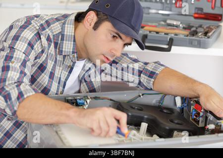Reparaturarbeiter, der an einer Waschmaschine arbeitet Stockfoto