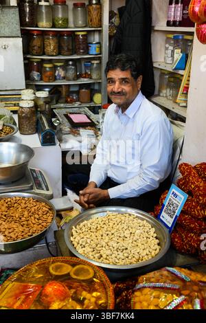 Jaipur, Rajasthan, Indien – 17. Februar 2025: Indischer Händler verkauft Gewürze und Nüsse in einem Geschäft auf dem Tripolia Basar. Stockfoto