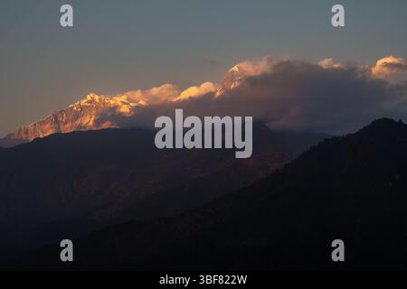 Ein atemberaubender Blick auf die schneebedeckten Gipfel von Annapurna I. und Annapurna South, wenn die Wolken sanft die Berge im großen Himalaya in Nepal umarmen. Stockfoto