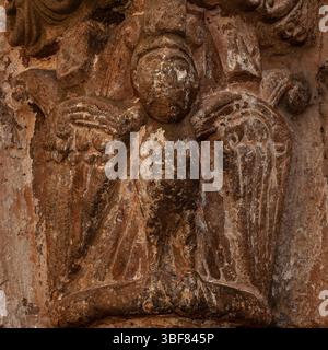 Flecken und Bruchstücke der antiken Farbe sind auf dem Skulpturenvogel mit menschlichem Gesicht und talonierten Füßen erhalten, der auf der Hauptstadt des berühmten spanischen romanischen Nordportals aus dem 12. Jahrhundert n. Chr. von Iglesia de San Salvador in Agüero, Provinz Huesca, Aragon, Spanien thront. Die Schnitzereien der Eingangstüren werden dem Bildhauer zugeschrieben, der als Meister von Agüero bekannt ist. Stockfoto