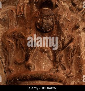 Lächelndes katzenförmiges Gesicht auf zwei miteinander verbundenen Löwen mit einem Kopf, der auf der Hauptstadt des 12. Jahrhunderts n. Chr. geformt wurde, um Tympanon und Archivolte des spanischen romanischen Nordportals von Iglesia de San Salvador oder der Kirche von San Salvador in Agüero, Provinz Huesca, Aragon, Spanien zu stützen. Reich geschnitzte Tür, die dem Bildhauer zugeschrieben wird, der als Meister von Agüero bekannt ist. Stockfoto