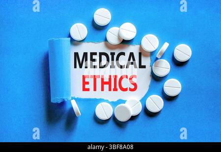 Medizinethik-Symbol. Konzeptworte medizinische Ethik auf wunderschönem Whitepaper. Weiße Tabletten. Wunderschöner blauer Hintergrund. Medizinisches gesundes lifestyl Stockfoto