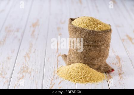 Bio-Couscous im Sack. Sack mit Bio-Couscous. Trockener Couscous in Sackleinen und Haufen Couscous. Stockfoto