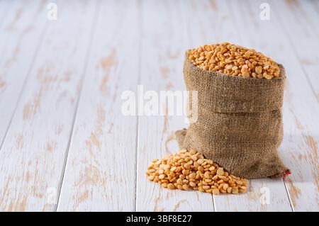 Trockene gelbe Erbsen im Sackbeutel. Sack mit organischen trockenen gelben Erbsen. Organische gelbe Erbsen in Sackleinen und Erbsenhaufen. Stockfoto