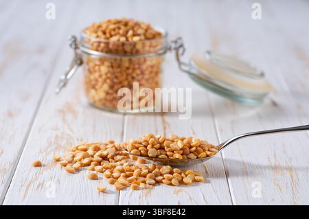 Metalllöffel mit rohen getrockneten Erbsen auf einem Leuchttisch, selektiver Fokus. Stockfoto
