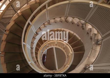 Ein Hochwinkelfoto fängt die faszinierenden, abstrakten Muster einer Wendeltreppe ein, während sie hinabsteigt. Stockfoto
