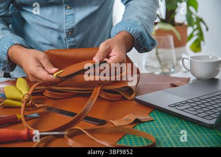 Ein Handwerker steckt eine Tasche in eine Ledertasche, arbeitet in seiner Werkstatt Stockfoto