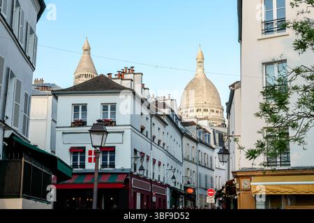 Ein belebter Blick auf die Straße von Montmartre, Paris, mit Blick auf die Basilika Sacré-Cœur, die mit der roten Markise und dem Zeichen des historischen 'L Stockfoto