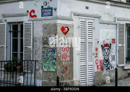 Eine Straßenecke im europäischen Stil mit weißen Wohnhäusern, die mit verschiedenen Straßenkunst-Stücken, Graffiti und Schildern geschmückt sind. Die Szene Stockfoto