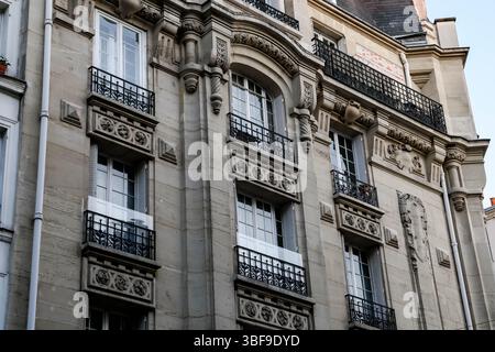 Detaillierter Blick auf ein elegantes Pariser Apartmentgebäude mit traditioneller Architektur, komplizierten Steinschnitzereien und klassischem Schmiedeeisen Stockfoto