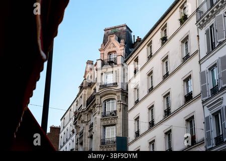 Eine flache Perspektive, die die Pracht typischer Pariser Apartmenthäuser in Richtung eines klaren blauen Himmels einfängt und betont Stockfoto