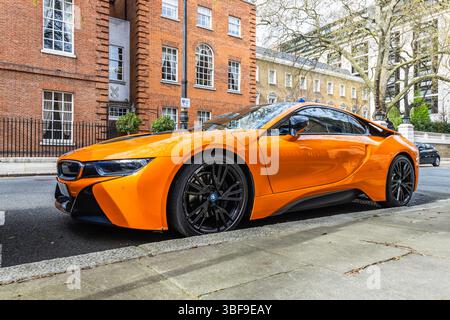 Lebhafter orangefarbener BMW i8 Sportwagen in der stilvollen London Street. London, UK, 6. April 2024 Stockfoto