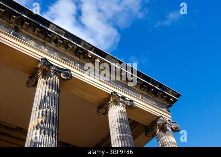 Flacher Blick auf alte Steinsäulen mit verzierten Kapitellen unter einem klaren blauen Himmel. Stockfoto