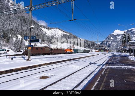 Züge und Gleise im Schnee am Bahnhof Kandersteg an der Lötschbergbahn mit Blick auf die Berge oberhalb des Kandertals, Berner Oberland, Schweiz Stockfoto