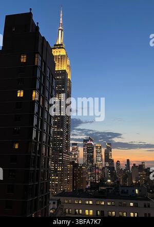 Stadtbild eines klaren Frühlingsabends mit dem beleuchteten Empire State Building im Vordergrund und den Wolkenkratzern von Hudson Yards im Hintergrund, die nach Westen schauen, 2025, NYC, USA Stockfoto