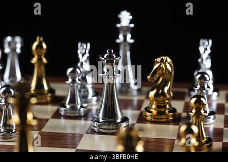 Goldene und silberne Schachfiguren auf hölzernem Schachbrett. Intellektuelles Duell und taktischer Kampf im Geschäft. Strategieplanung, Führung und Teamarbeit Stockfoto