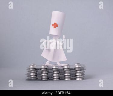 Eine Krankenschwester aus Papier steht auf einem Stapel Pillen, einer Kopie des Raumes Stockfoto