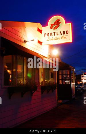 Eine Hummerhütte an der Küste von Portland, Maine, leuchtet vor einem Abendhimmel Stockfoto
