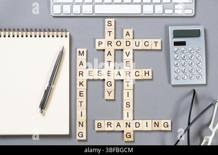 Konzept für das Produktbranding mit Wörtern aus Cubes. Stillleben des Büroarbeitsplatzes mit Kreuzworträtsel. Flache graue Oberfläche mit Computertastatur und Calcul Stockfoto