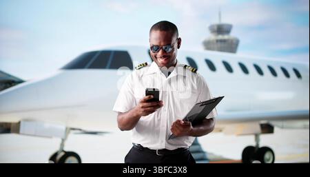 Afroamerikanischer Pilot Lächelt Am Flughafen, Bevor Er In Den Privatjet Steigt. Stockfoto