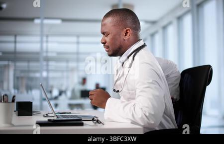 Schwarzer Mann Mit Schlechter Haltung, Der Im Büro Sitzt Und Rückenschmerzen Hat Stockfoto