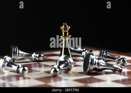 Goldenes Schach besiegt Silberfiguren auf hölzernem Schachbrett. Intellektuelles Duell und taktischer Kampf im Geschäft. Strategieplanung, Führung und Tee Stockfoto