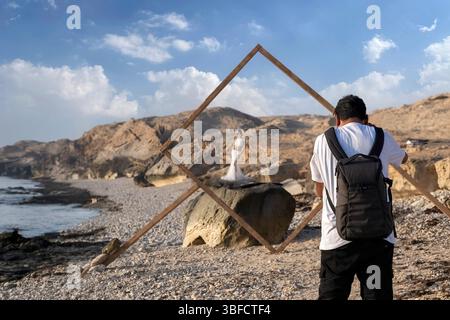 Der Fotograf fotografiert ein Brautmodell am Strand Stockfoto