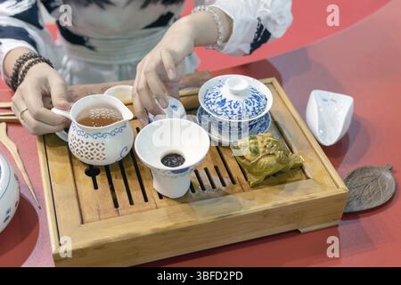 Chinesische Teezeremonie. Das Mädchen gießt den Tee aus dem Wasserkocher in die Tasse Stockfoto